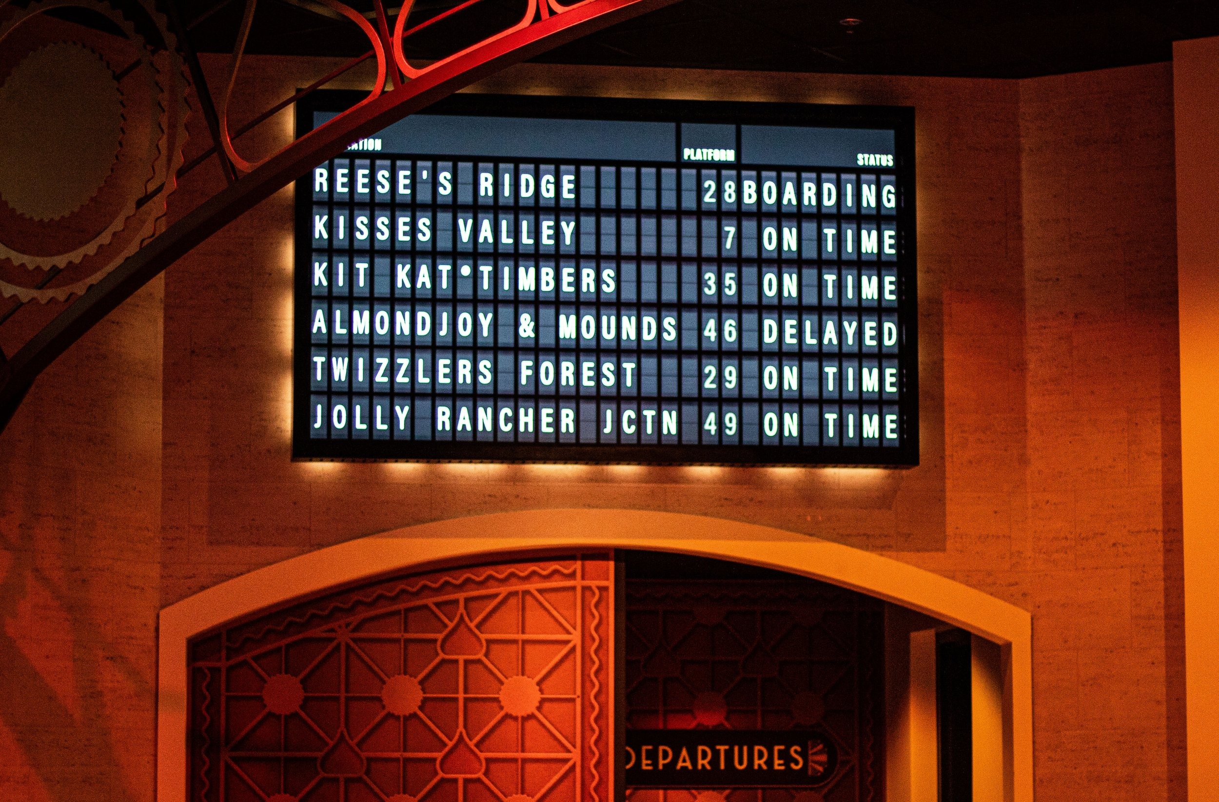 Departures board listing all six candy-themed lands