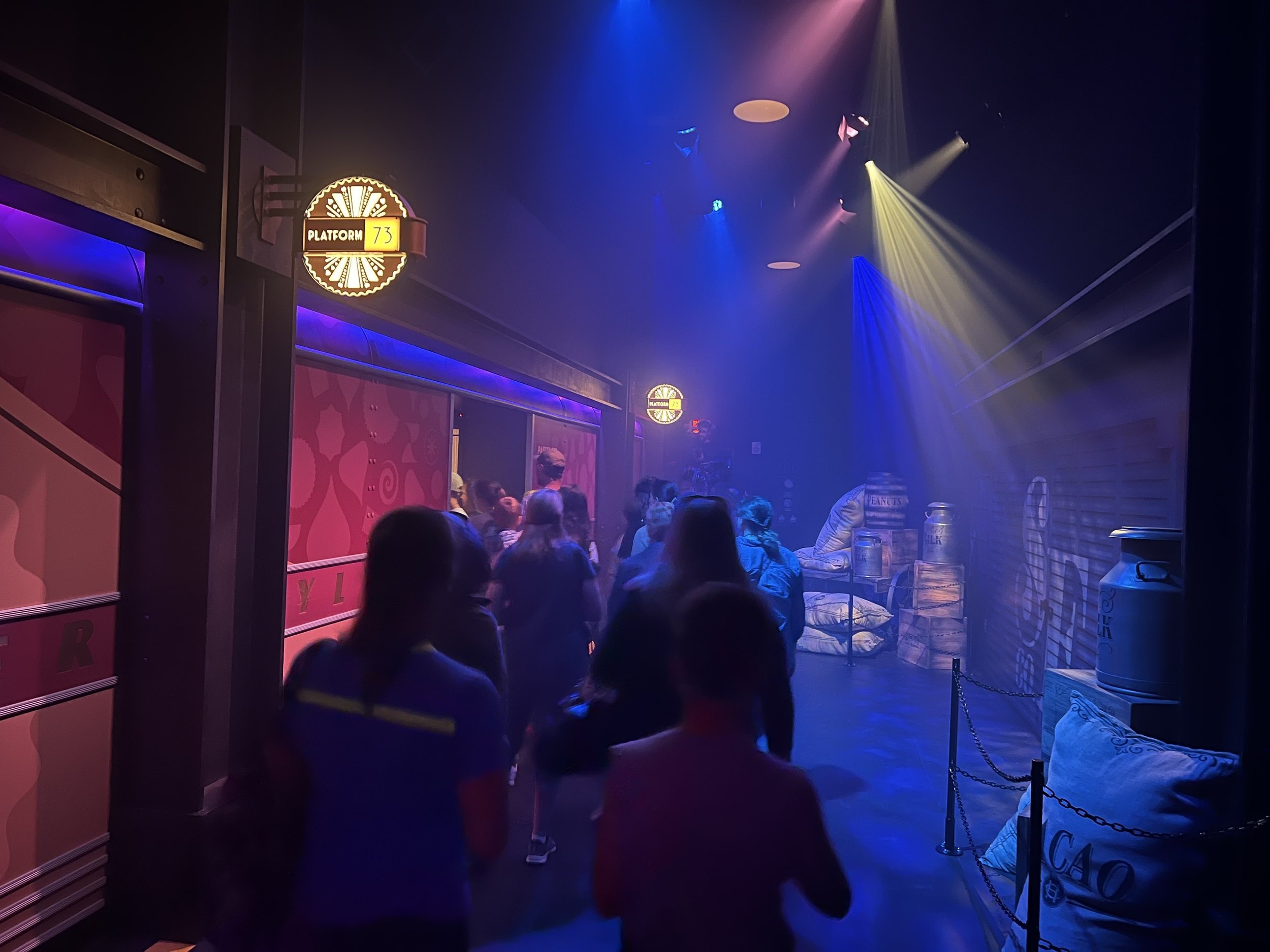Guests queuing toward the platform, lit in blue and purple