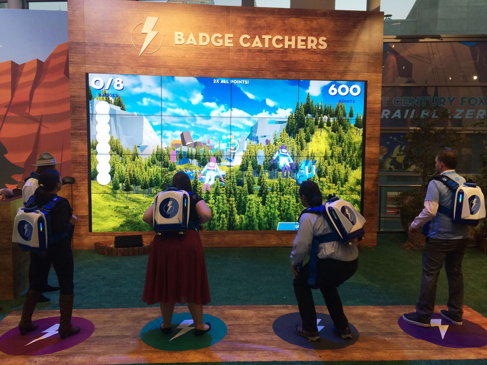 Guests wearing jetpack rigs playing Badge Catchers in front of the big screen at Dreamforce