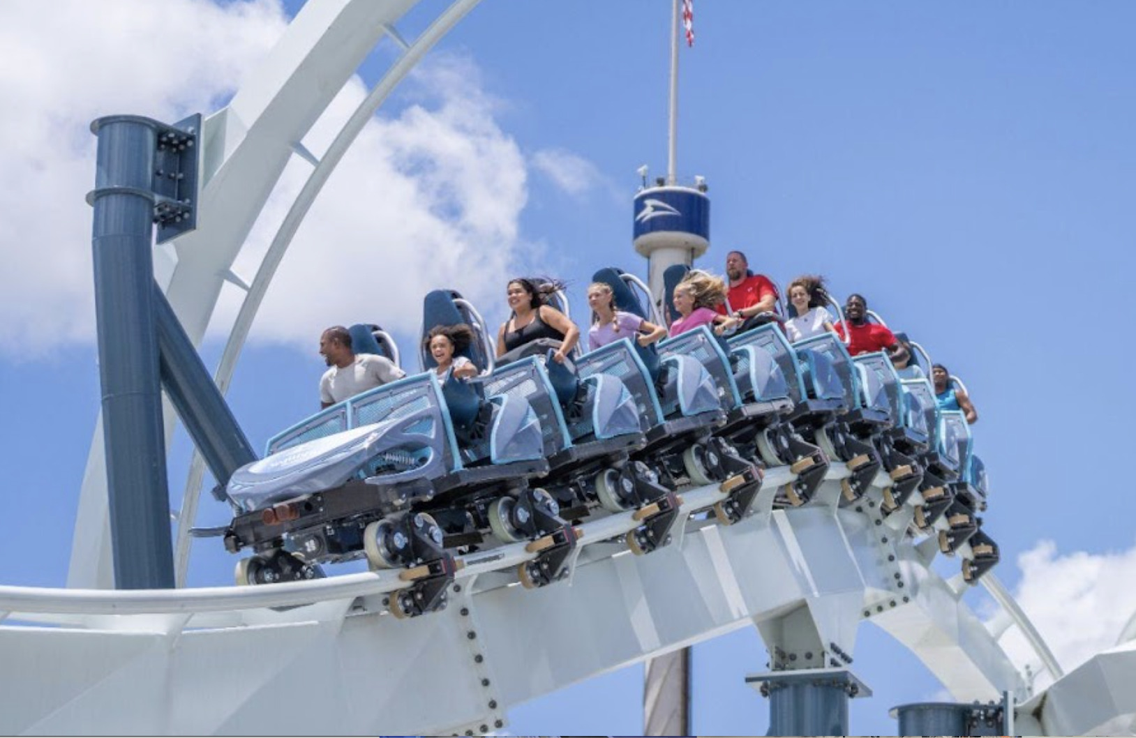 The Penguin Trek coaster train cresting the track against a blue sky